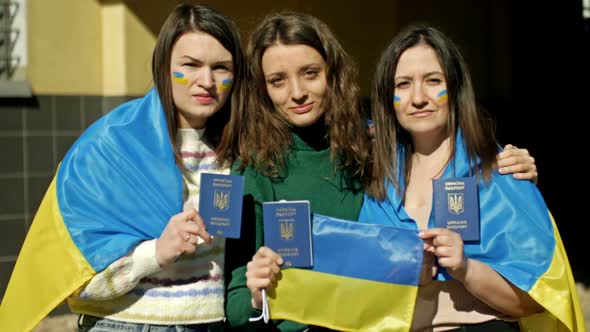 Three Women Covered with the Flag of Ukraine Stand Embracing