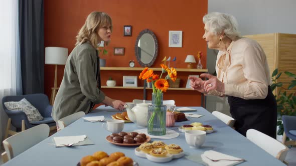 Woman Talking with Grandma while Preparing Holiday Dinner Table alt