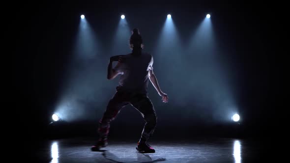Man Enjoying Hip Hop Moves in Dark Studio with Smoke and Lighting. alt