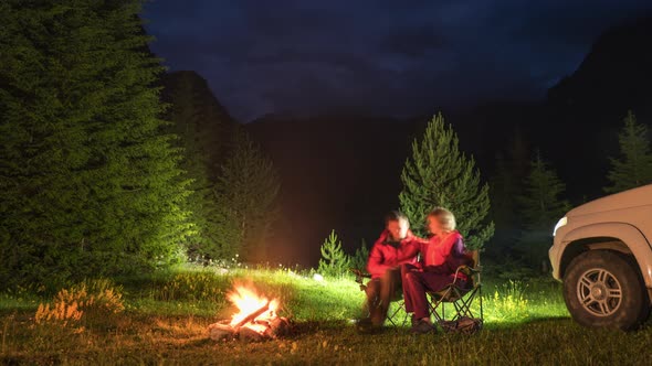 Time-lapse of Couple Chatting By Bonfire in Camping in Mountains in the Evening 