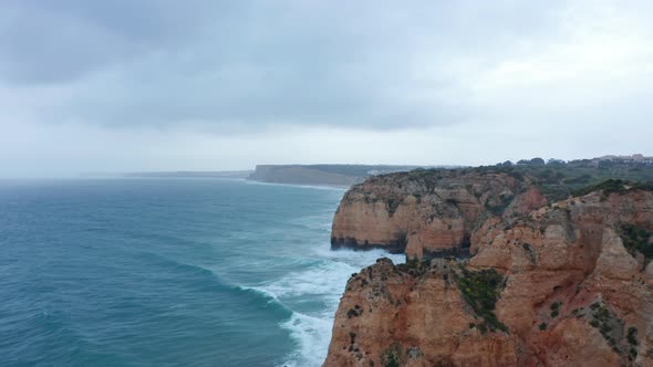 Aerial View of Ocean and Rocky Cliffs in Lagos Portugal Drone Shot with Cloudy Weather alt