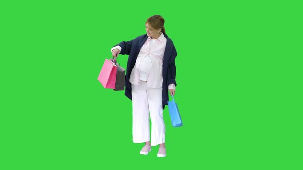 Beautiful Happy Exciting Pregnant Blonde Woman Holding Shopping Bags on a Green Screen, Chroma Key alt