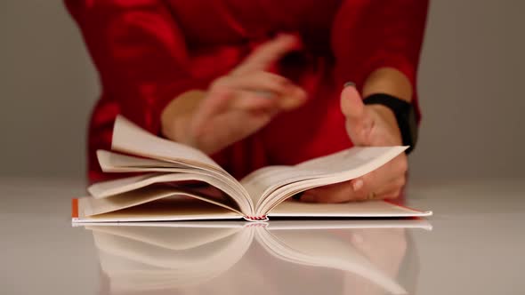Young Woman in Red Robe Turns Paper Book Pages with Hands alt