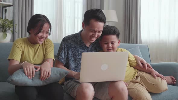 Happy Father With Two Little Children Using Laptop Together, Sitting On Sofa At Home alt