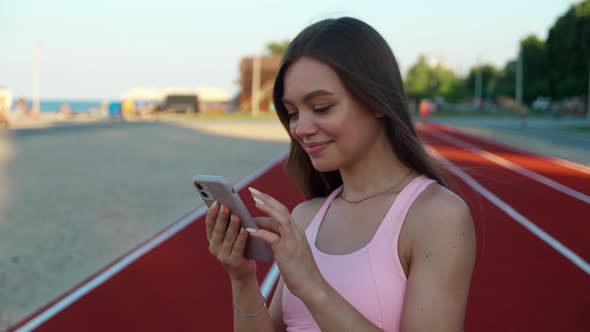 Sporty Young Woman Using Mobile Phone at Stadium alt