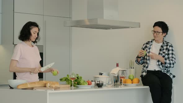 Casual Middle Age Women Friends Cooking Healthy Salad Meal in Kitchen Talking and Dancing Rbbro alt