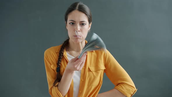 Slow Motion of Joyful Young Lady Playing with Bunch of Cash Then Throwing Money on Gray Background alt