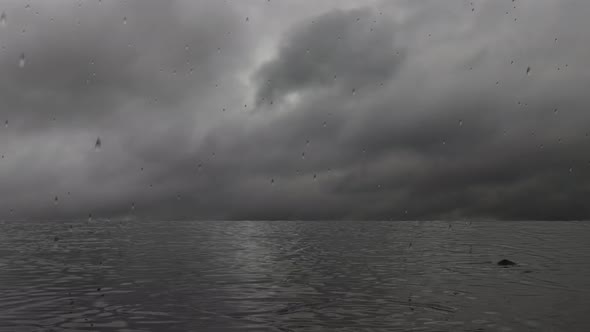 Rain on the lake, gray storm clouds. Rain intensifies on a sea of water with reflections