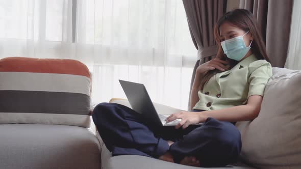 Happy young asian woman in protective mask using laptop to video call or facetime to talk friend alt