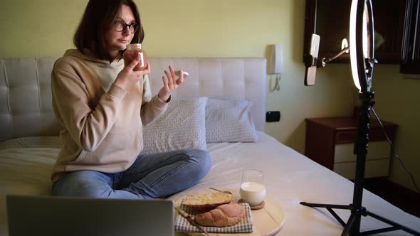 Girl food blogger showing a jam and recording vlog on digital smartphone alt