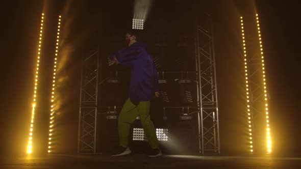 Trendy Young Hip Hop Dancer in a Protective Medical Mask. Hip Hop Street Dance on a Stage in Dark alt