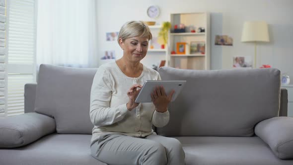 Retired Female Scrolling Tablet Application Relaxing at Home, Shopping Online alt