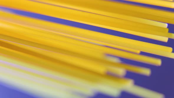 Close Up of Raw Unprepared Spaghetti Rotating on Blue Background alt