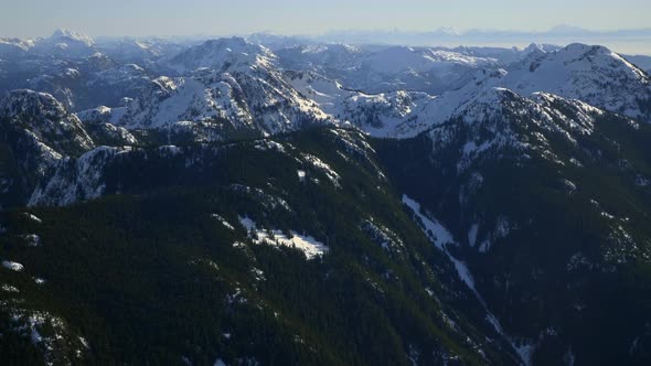 Aerial: Snowy Mountains between Vancouver city and Whistler Mountain during sun. Wide shot over Gari alt