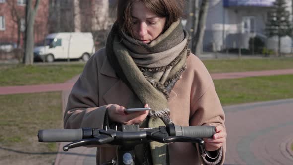 Woman using rental scooter via smart phone