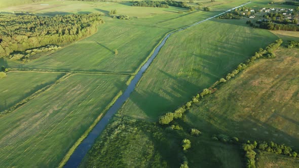 Flight Over The River In The Valley. A Village In The Middle Of The Forest Is Visible In The Distanc alt
