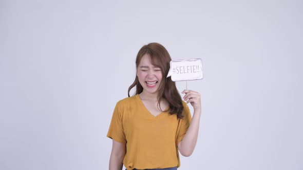 Happy Young Beautiful Asian Woman with Selfie Paper Sign alt