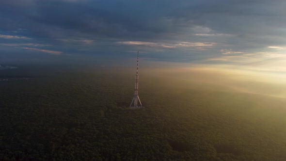 Sunrise aerial view on tv tower in cloudy forest