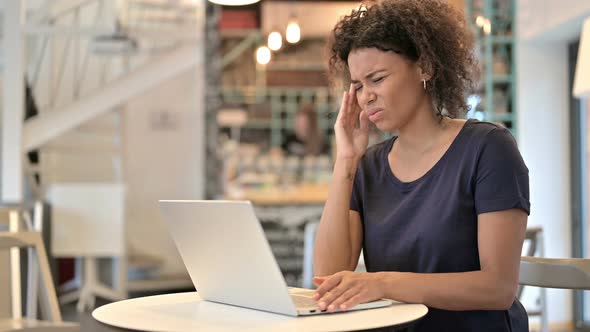 Young African Woman with Headache Using Laptop in Cafe  alt