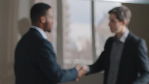 Blurred Two Multiracial Multinational Businessmen Talking in Office Shaking Hands Unfocused View alt