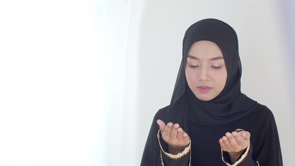 Happily young Muslim female praying with Islamic faith 