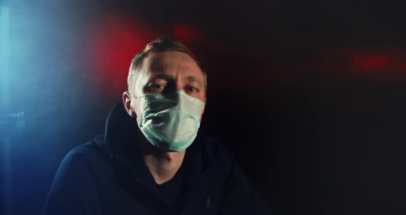 Person Masked Portrait Looking at Camera Color Lights. Corona Virus Covid-19 . alt