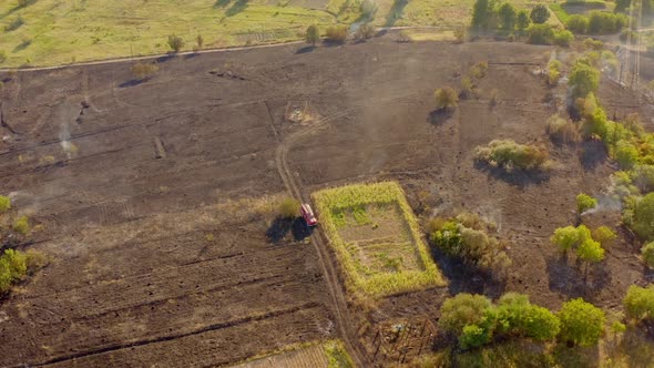 Aerial view of fireman truck working on the field on fire alt