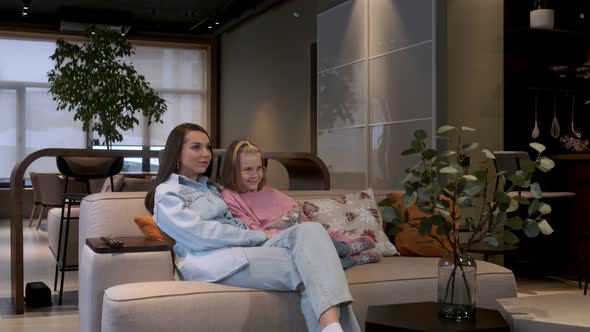 Happy young woman sitting on cozy couch with adorable little cute daughter. alt