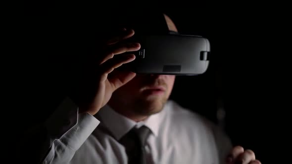 Man in a Shirt and Tie with a Headset Goes Into the Virtual World Sitting in the Office in the Dark alt