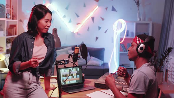 Two Multiethnic Musicians Creating New Song in Home Recording Studio alt