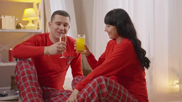 Happy Man Clinking Champagne Glass with Woman Drinking Orange Juice alt
