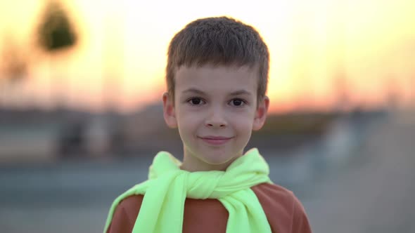 Male Portrait Cute Smiling Schoolboy Stands Outdoors in Light of Sun in Sunset