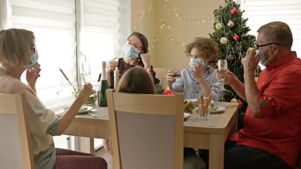 eFamily Is Celebrating Christmas Wearing Protective Masks. Everyone Congratulates Each Other and alt