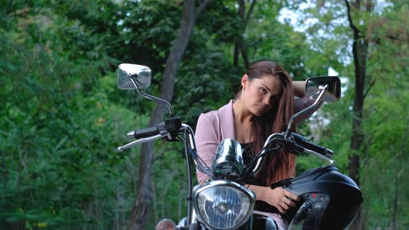 Beautiful Woman On A Motorcycle Takes Off Her Helmet And look In The Mirror alt