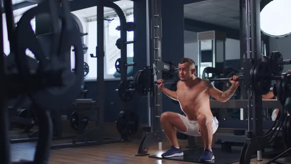 Young Fit Man Bodybuilder Doing Barbell Squats at Gym