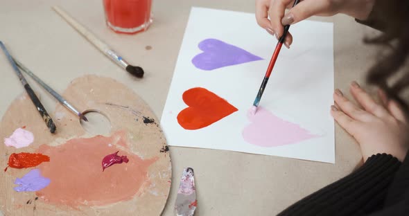 Unrecognizable Girl Drawing Hearts on Paper for Saint Valentine's Day