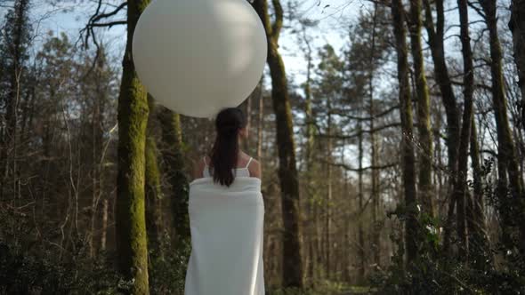 Woman Walking In The Forest With White Balloon