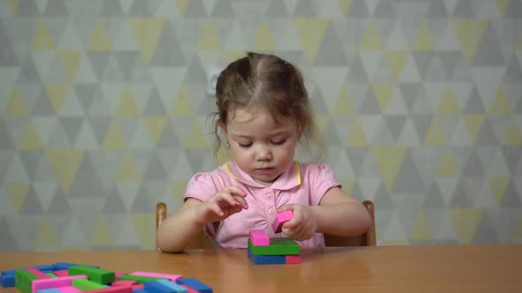 a Little Girl Collects Colored Jenga at Home