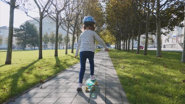 Little Girl is Slowly Skateboarding in Protective Helmet Steadicam Shot