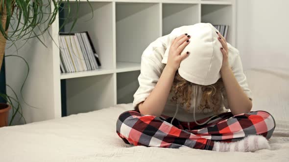 Teenage Girl Sits Alone on the Bed and Cries Covering Her Face with Her Hands