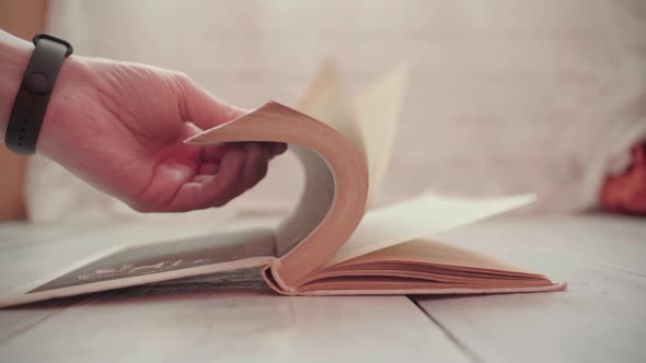 Man's Hands Turn the Pages of a Book alt