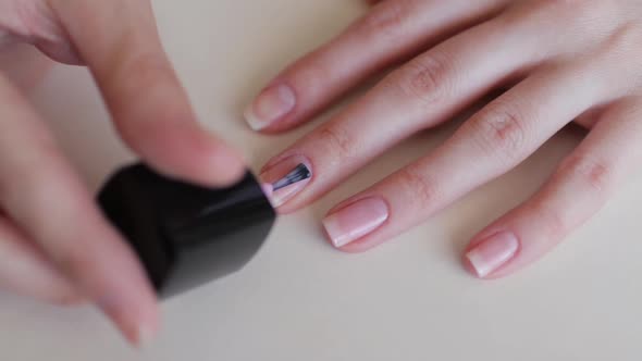 Woman Paints Nails with Nail Polish While Doing Manicure