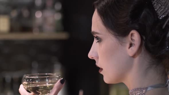 Closeup Portrait of a Young Attractive Woman in a 1920s Style Drink Wine or Champagne at the Bar alt