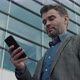 Dreamy confident Businessman working on Smartphone near big modern Office. - VideoHive Item for Sale