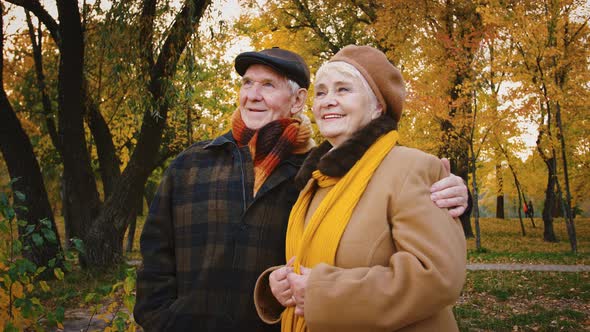 Retired Spouses Hugging Talking and Smiling While Looking at Picturesque Autumn Landscape of City alt