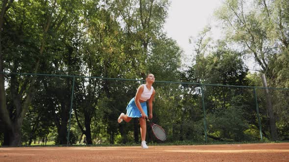 A Caucasian woman wearing tennis spending time on a court, playing tennis on a sunny day, holding te
