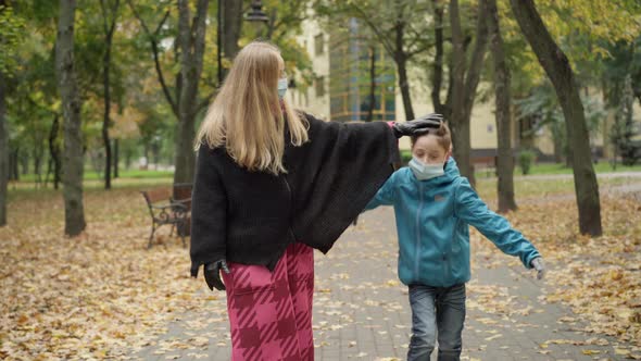 Portrait of Excited Caucasian Boy in Covid19 Face Mask Talking with Beautiful Woman Walking in alt