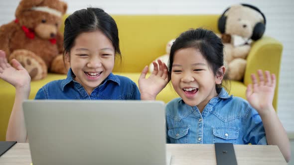Two sister Chinese girls are delighted as they watch. laptop, educational concept, ethnicity