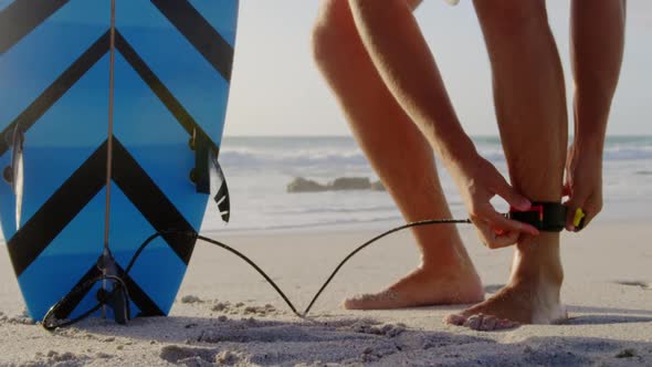 Man tying surfboard leash at beach in the sunshine 4k alt