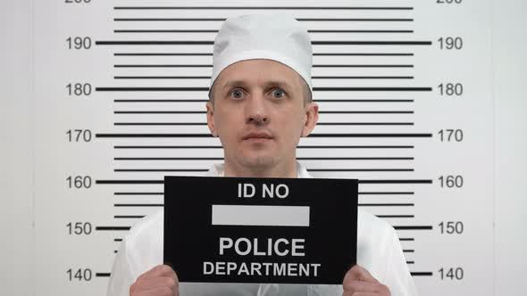 Mugshot of a Mad Doctor in a White Coat, at the Police Station alt